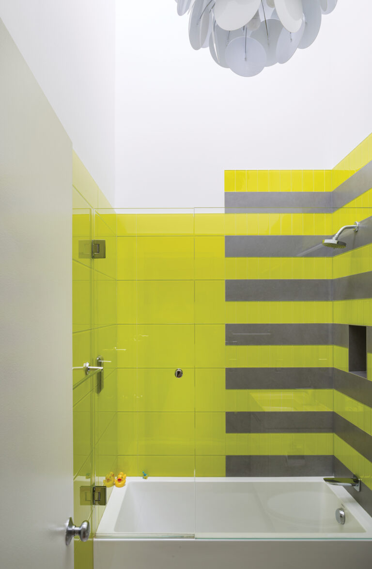 A child’s bathroom in a DC residence features large-format glass tiles in a bold hue.
