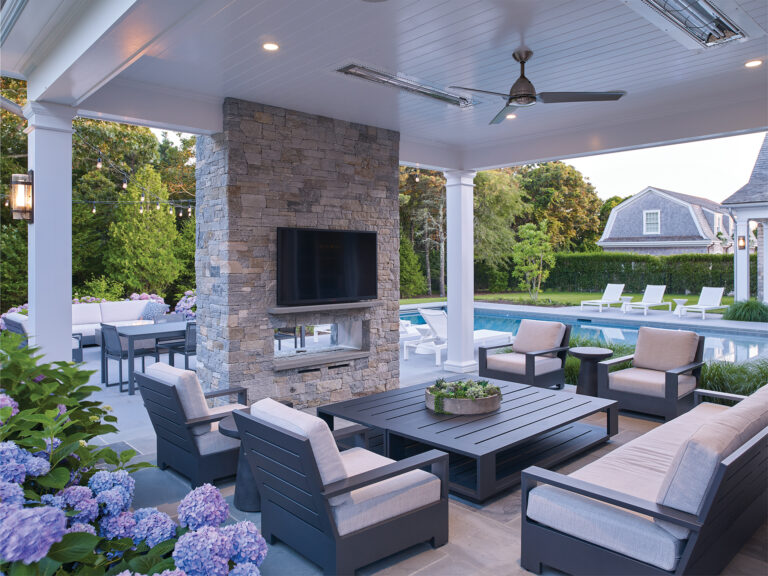An al fresco dining area centers on a stone fireplace that fosters year-round gathering.