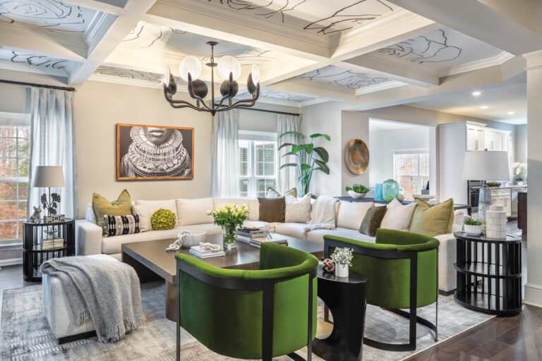 A chic living room exudes sophistication, comfort and creativity with eye-catching art, pops of color and dramatic ceiling coffers clad in graphic wallpaper.