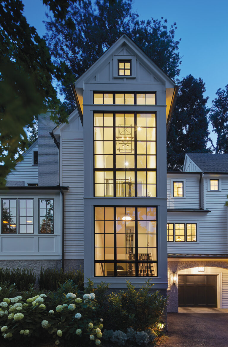 The home features a three-story glass stair tower with large, black sash windows.