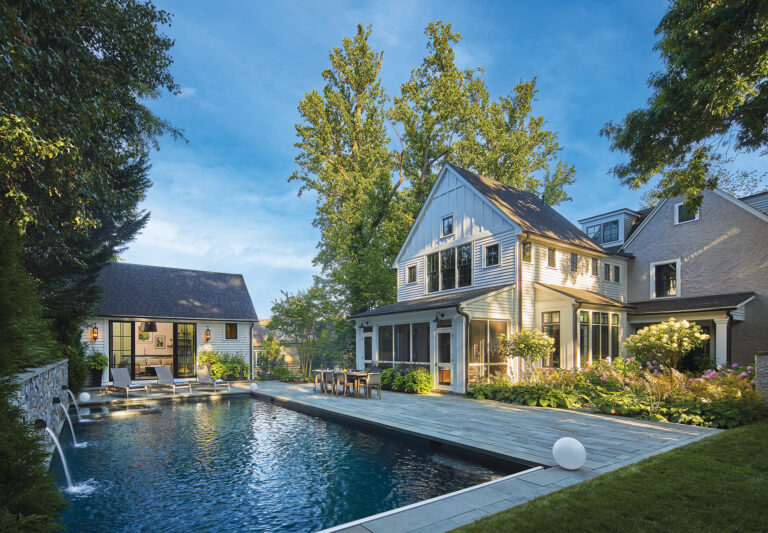 A backyard shot reveals the pool house and and adjacent home’s new addition with screened porch flowing out to the patio and pool.