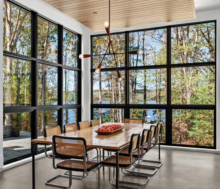 A Deep Creek Lake abode is oriented toward water views, with its light-filled dining area bordered by windows on three sides.