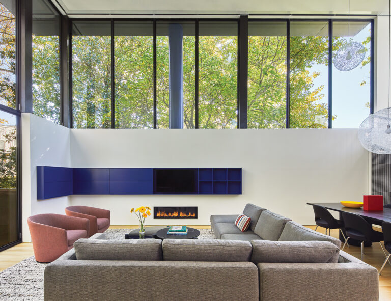 Inside, the house is organized around a double-height living area. Tall, south-facing windows welcome light while ensuring privacy.