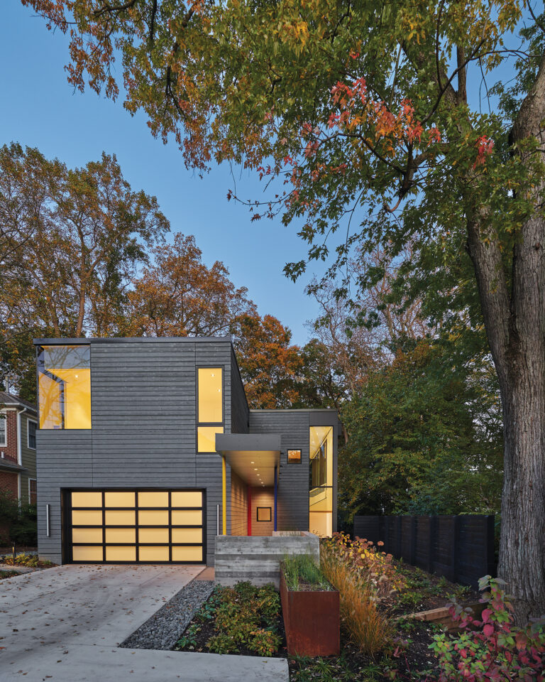 A projecting overhang, board-formed concrete walls and a new Corten steel planter create an approach to the red, pivot-door entry.