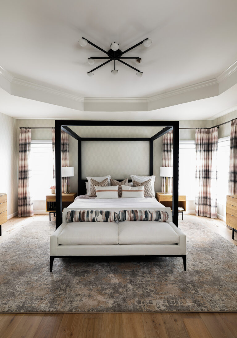 Layered patterns, an upholstered chenille bench and contemporary Visual Comfort lighting enliven a primary suite, part of a whole-house redesign.