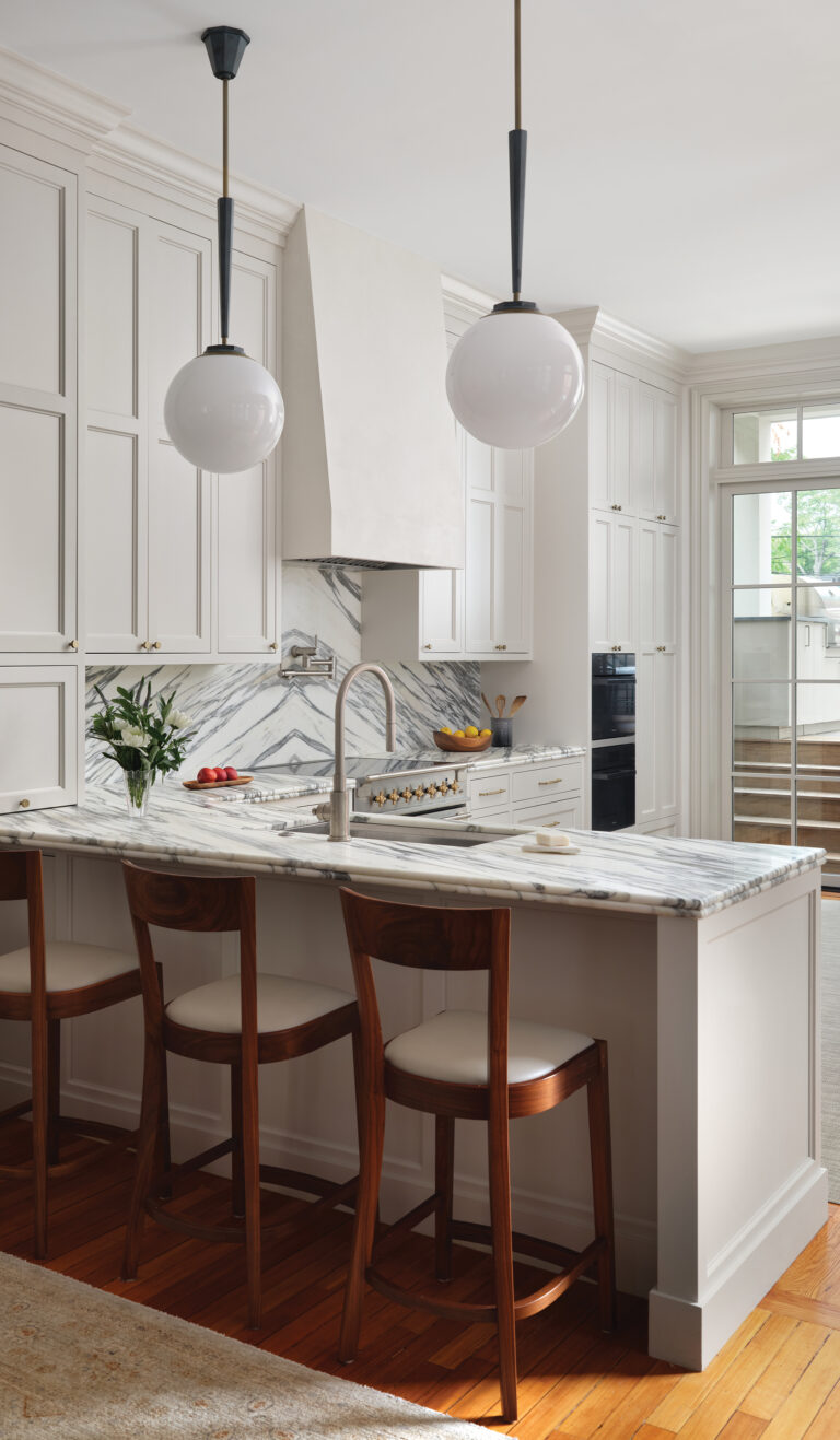 Bold, marble surfaces complement custom cabinetry in an elegant kitchen, part of a Dupont Circle row house renovation.