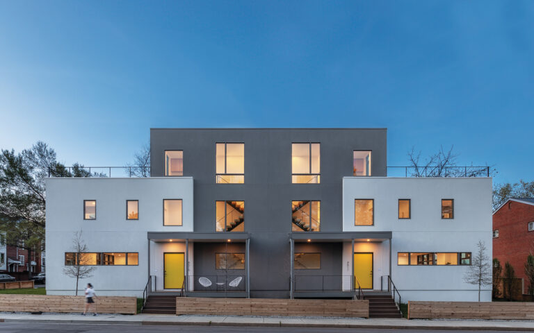 A modern, two-family house in Arlington creates distinctive curb appeal with contrasting stucco finishes, large entry doors and generous porches.