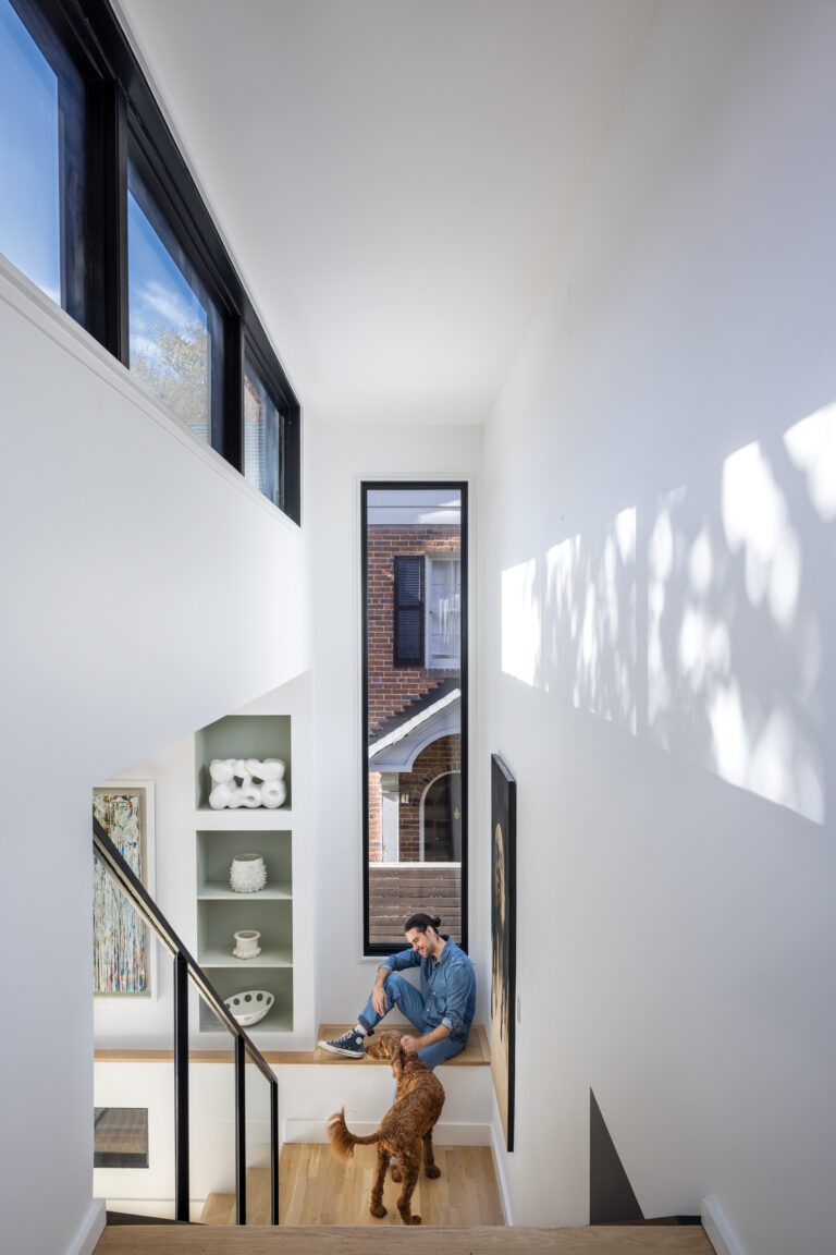 Clerestory windows in the Chevy Chase project cast patterns onto the staircase and facing wall, with its built-in shelving.
