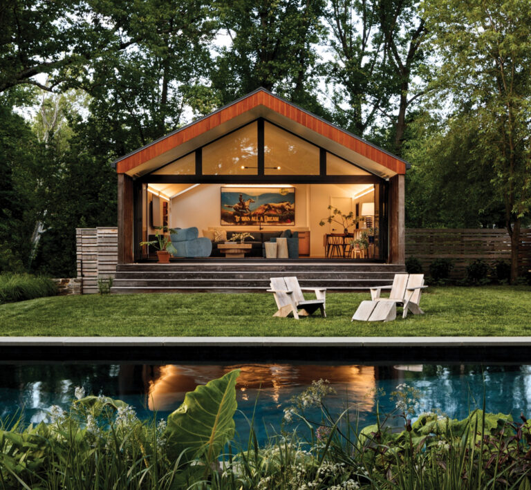 Foxhill Residence features a combined pool house and garage with a full-wall glass pivot door opening out to a landscaped pool deck.
