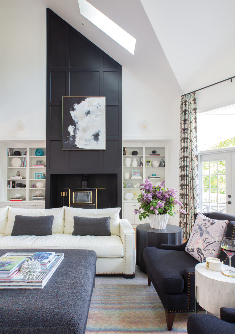 The interplay of black millwork and white vaulted ceilings in the double-height living room creates contrast, layered with tailored upholstery and brass accents.