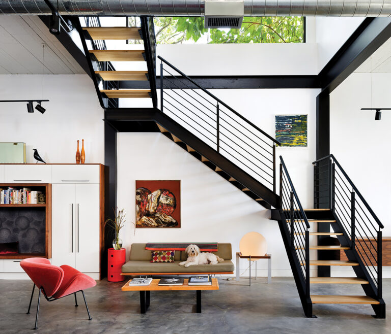 An open living area features steel beams that reinforce the concrete ceiling. Metal Specialties fabricated the steel stair frame.