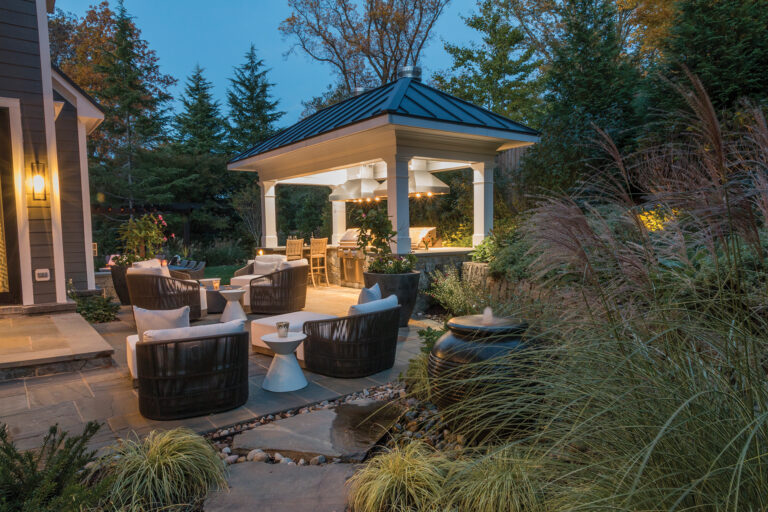 An outdoor kitchen is the hub of activity in a lush landscape.