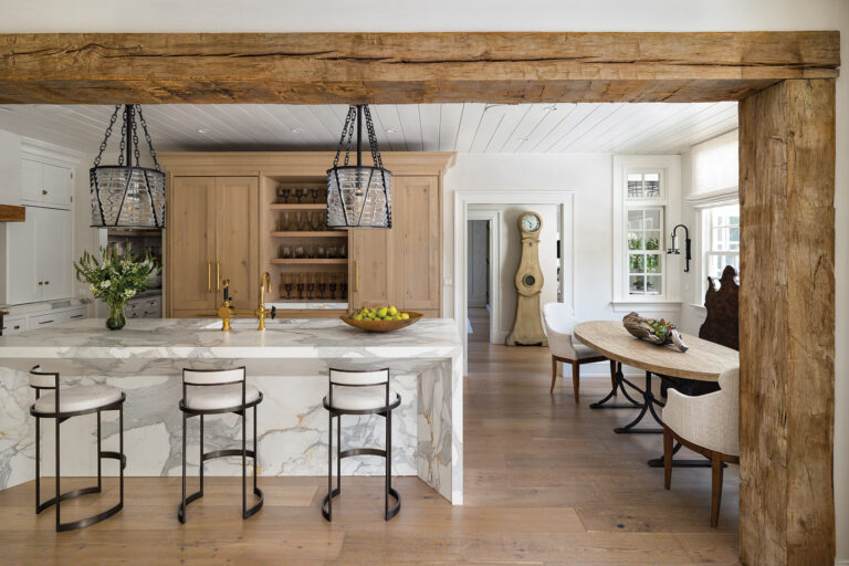 Marble surfaces offset white and wood cabinetry in an elegant kitchen that flows into the breakfast room and surrounding living spaces.
