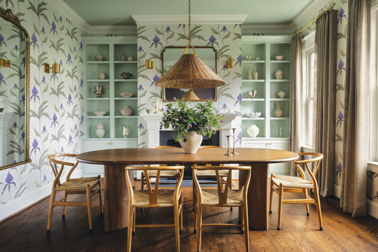 Mint walls and floral wallpaper create a garden vibe in a dining room layered with natural wood and wicker accents.