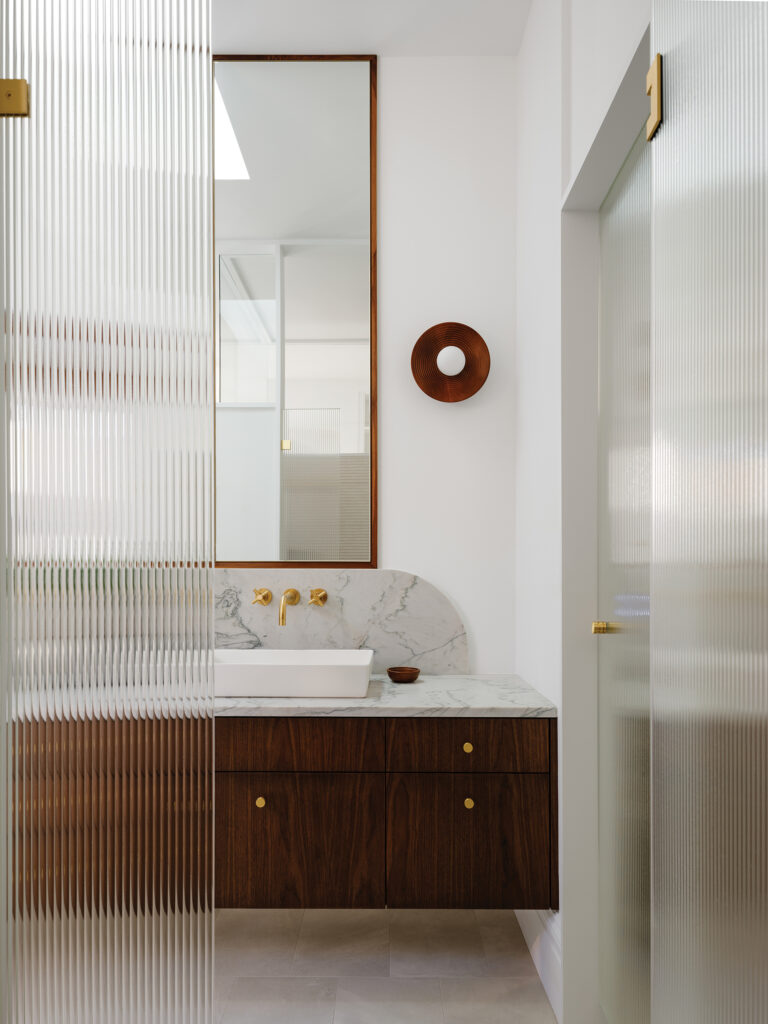 A primary bath on Capitol Hill boasts a sleek shower enclosure that imparts a modern touch without sacrificing the home’s timeless feel.
