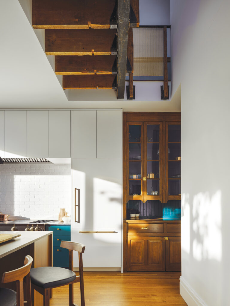 For a renovated kitchen in a Capitol Hill remodel, a rarely used back stair was removed to create a second-floor overlook. Skylights above bring light down into the first floor. A hutch that was original to the home was refinished and repurposed.
