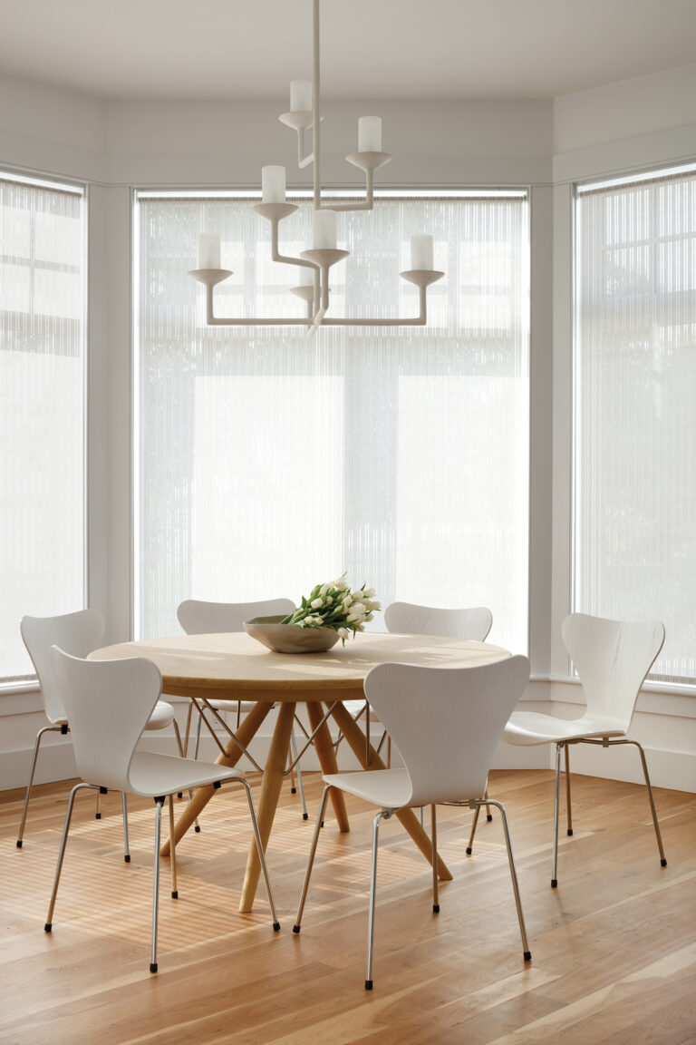 In the airy breakfast nook, a chandelier by Bourgeois Bohème Atelier hangs above a PP Mobler table and Fritz Hansen chairs.