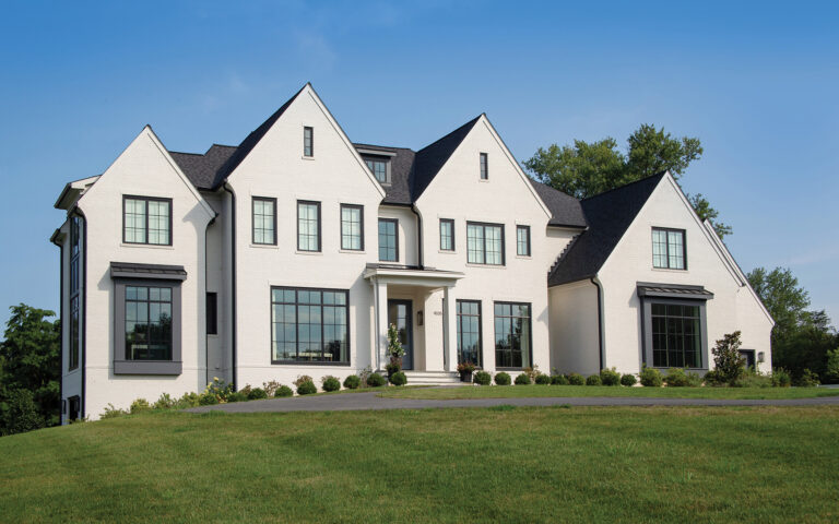A custom home in Potomac balances scale and  proportion with banks of windows facing front.