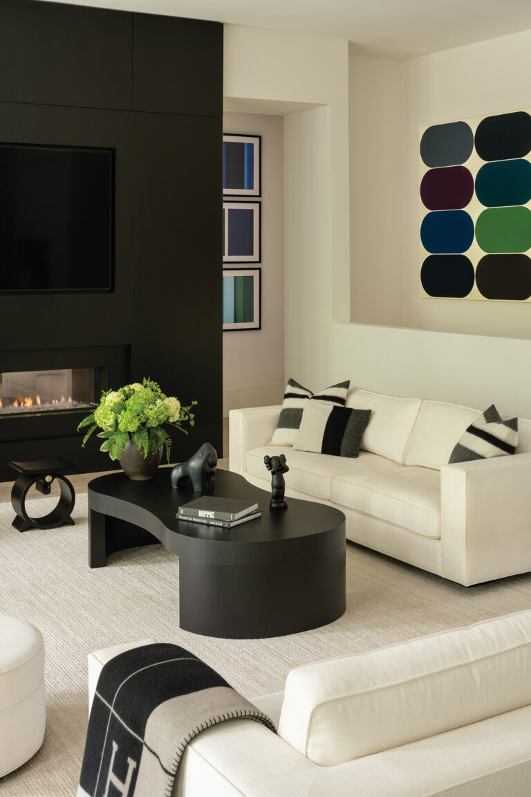 A neutral living room scheme offsets bold canvases; a panel of black-stained oak conceals a screen when not in use.