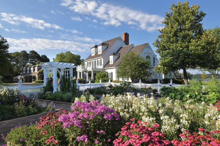 A picturesque white picket fence encloses a cutting and vegetable garden in the side yard of an Eastern Shore home.