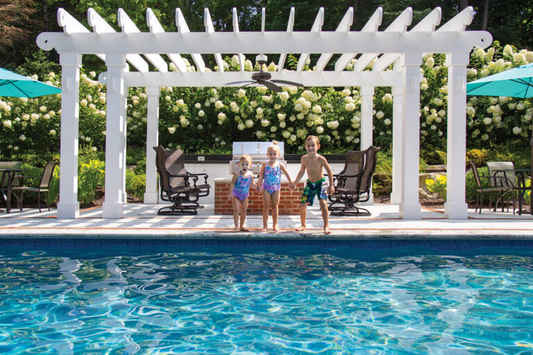 An outdoor kitchen is framed by a pergola and banked by Limelight hydrangea.