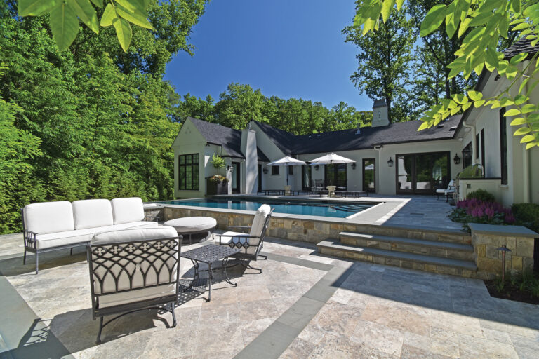 A patio promotes lounging beside a raised pool and travertine terrace.