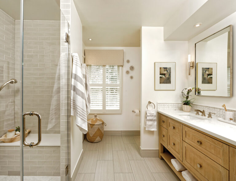A luxurious bath features a large custom shower and vanity with Rousseau bath sconces by Visual Comfort.