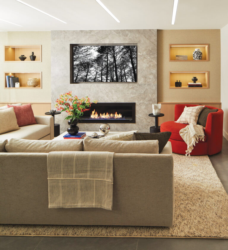 A stylish basement renovation features a modern fireplace flanked by built-in cabinetry that conceals ductwork while providing storage and space for a TV.