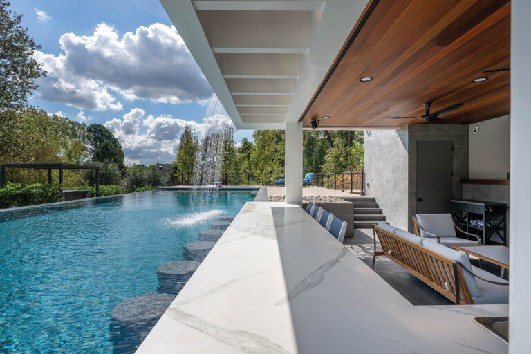 A modern, flat-roof structure in McLean connects to the adjacent infinity pool with a swim-up bar and waterfall.