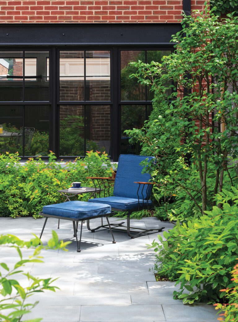 Comfortable seating tucks into plantings before a new carriage house.