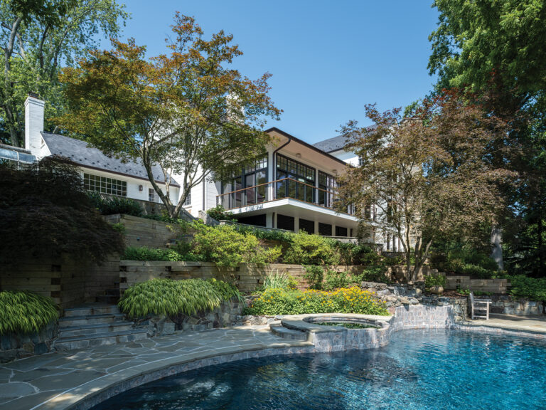 Perched above the pool and patio, a glassy, modern addition overlooks panoramic backyard views.