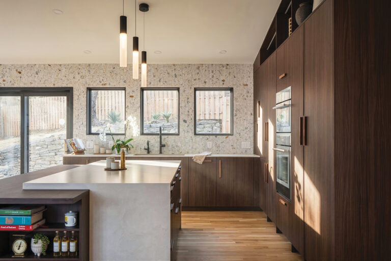 A Mid-Century Modern kitchen in Northwest DC showcases clean lines, a waterfall island, textured backsplash and slim pendant lighting.