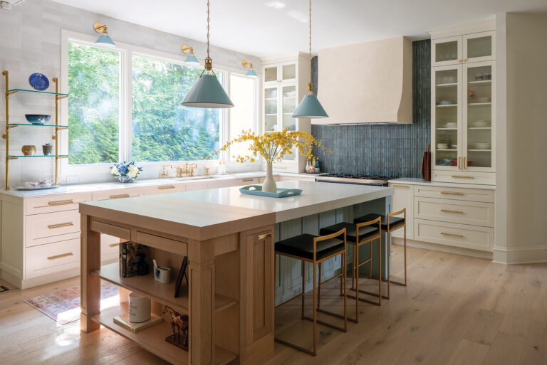 Inspired by Mediterranean design, a Bethesda kitchen embraced a soft palette via cream cabinetry, a blue-tiled range wall and brass fixtures.