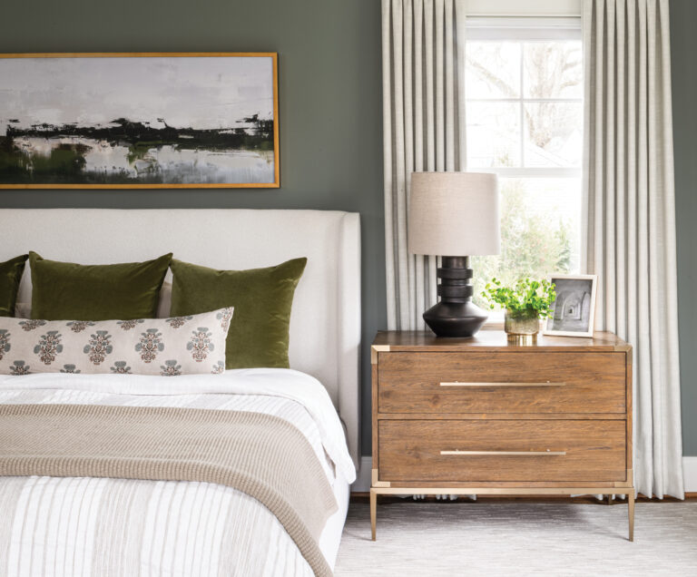 A primary bedroom boasts warm, olive-gray walls that contrast with a Universal bed upholstered in white and oak nightstands.
