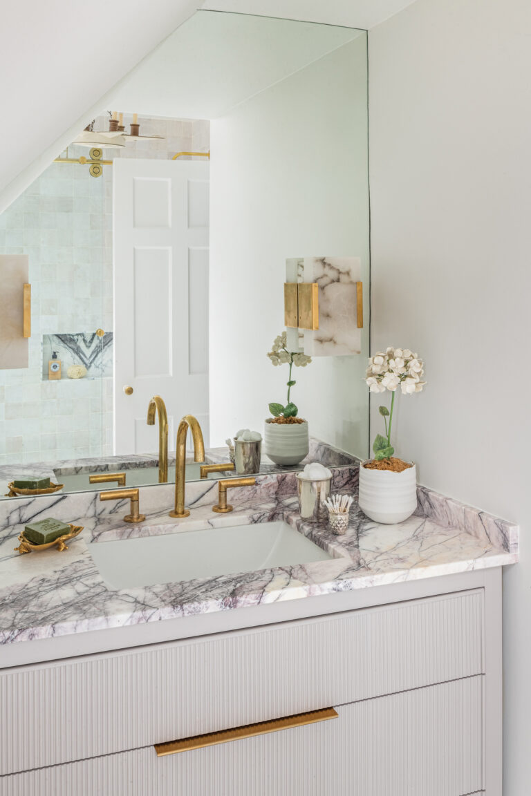 An NKBA award-winning bath features a custom marble countertop from Petra Stone, Visual Comfort sconces and unlacquered brass fixtures.