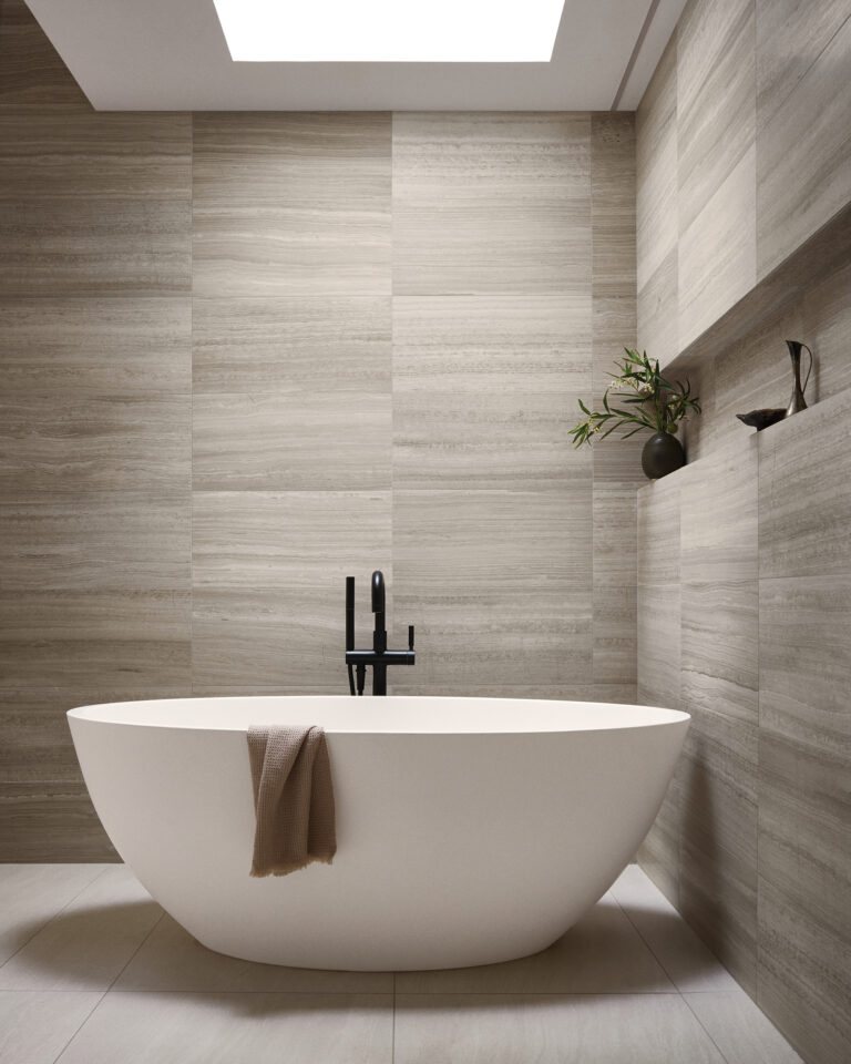 Large-format marble tiles are a backdrop for a Badeloft soaking tub, perched on a complementary porcelain-tile floor in the primary bath.