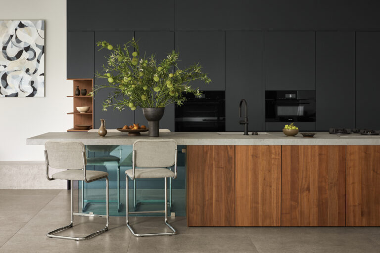 In the streamlined kitchen, a Dekton island countertop extends to a cantilevered breakfast bar supported by a glass panel.