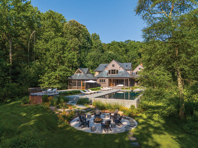 The slope of a Rock Hall site required that one end of the 55-foot-long pool rise five feet above ground. Fieldstone boulders and flagstone lead to a firepit surrounded by Black Eyed Susans and switchgrass.