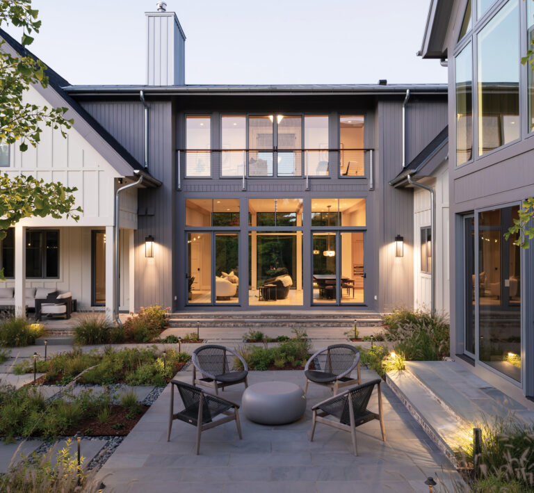 A courtyard garden is grounded by bluestone terraces stitched together with stepping-stones and softened by perennial planting. Light-filled glass openings in the architecture take advantage of the garden view.