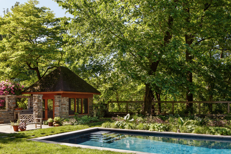 Designed as an extension of the surrounding landscape, the pool garden blends naturalistic plantings, historic architecture, and a dark-bottom pool that reflects the colors and textures of the gardens beyond.