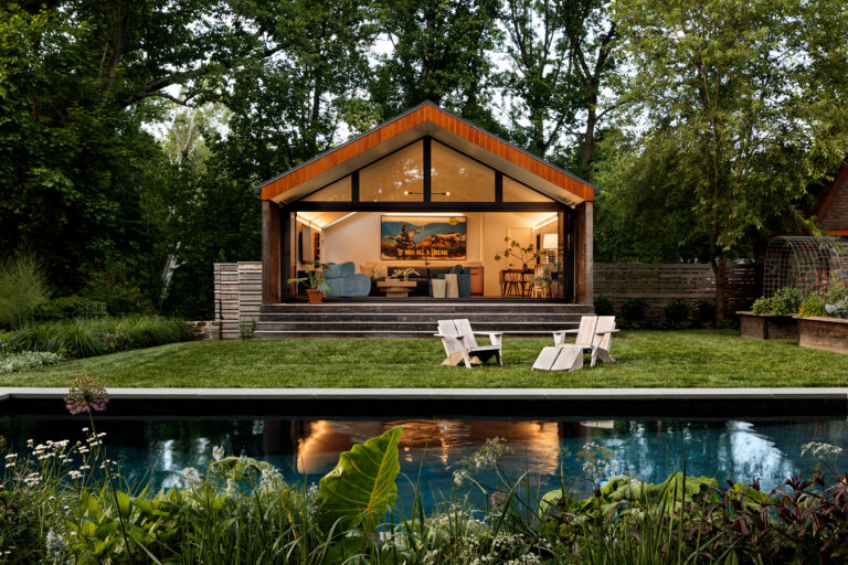 The interplay of stone, concrete, galvanized steel, and a custom fence creates a rich material palette that grounds the pool garden, while naturalistic plantings blur the boundaries between architecture and landscape.