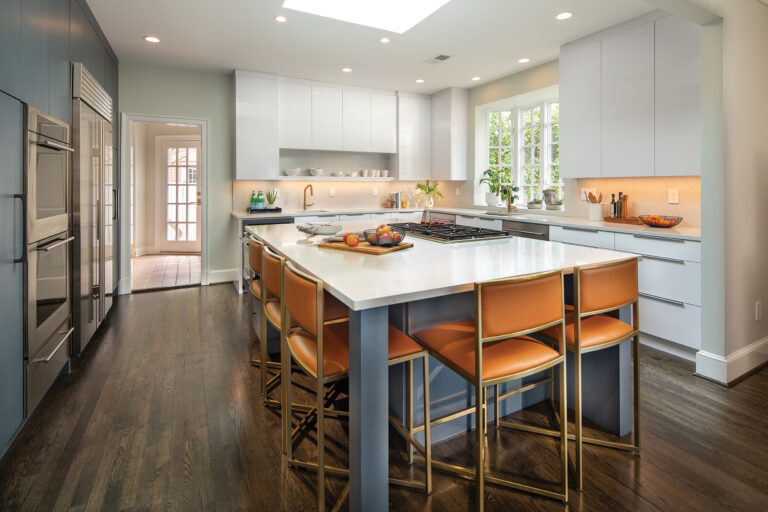 A light color palette adds contemporary flair to a traditional kitchen where a high-gloss finish on the perimeter cabinets contrasts with the low-sheen island and accent wall. 