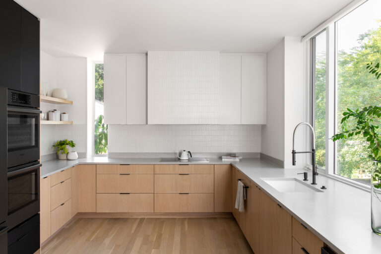 Pale cabinetry and a generous window ledge set the tone for this sun-drenched kitchen, where clean lines and natural light keep the space connected to the garden beyond.