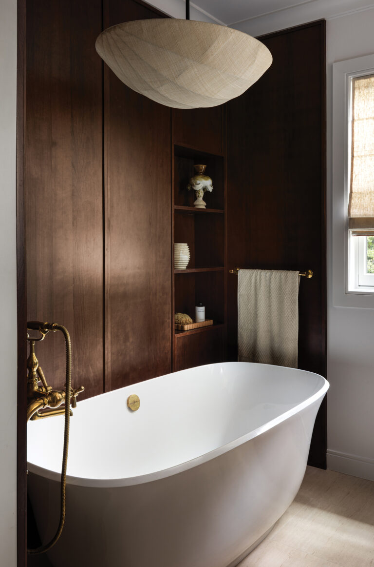 A custom walnut storage alcove beside a freestanding tub elevates a primary bath in DC. 