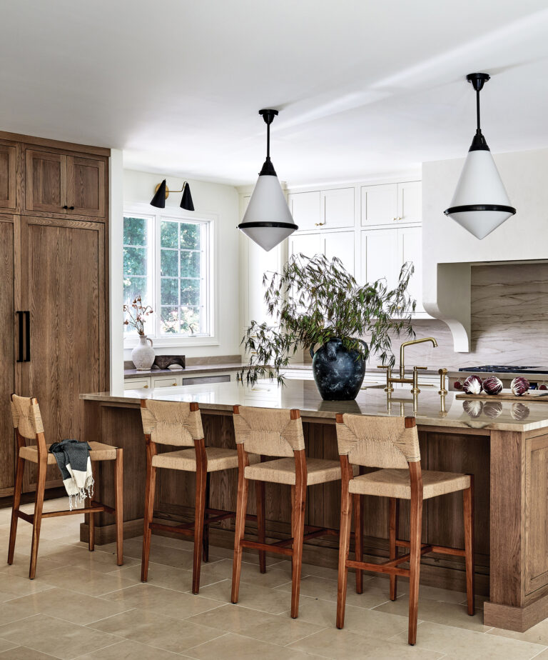 A Forest Hill, Maryland, kitchen is elevated by custom white cabinetry, quartzite backsplash, woven stools and chic pendants.