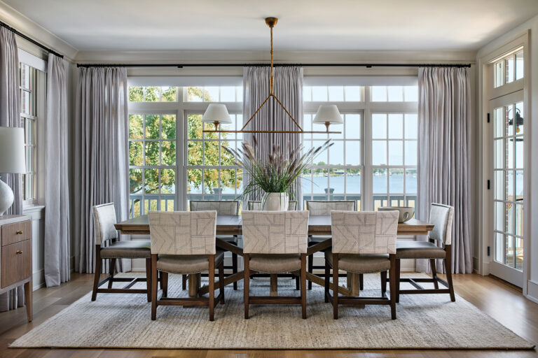 Tailored drapery, a brass chandelier and upholstered dining chairs blend harmoniously in a dining room on the Chester River.