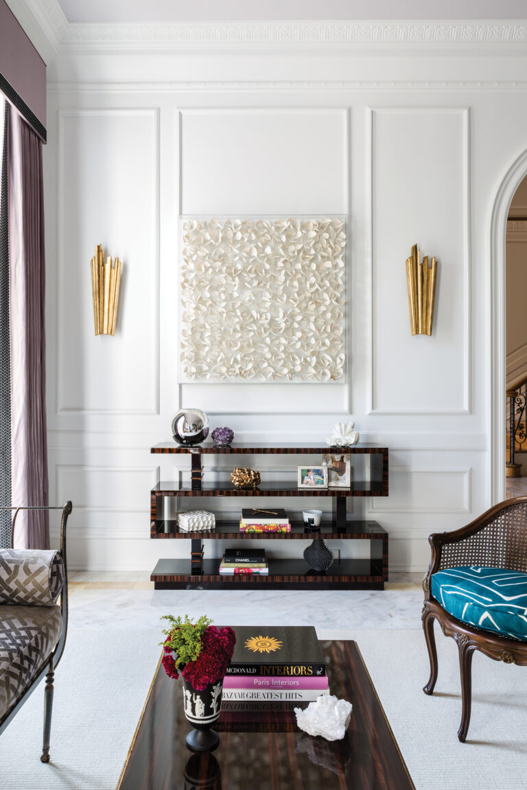 A French Modern aesthetic enlivens a Potomac living room where architectural detailing is a backdrop for luxe antique pieces and shadow wall art.